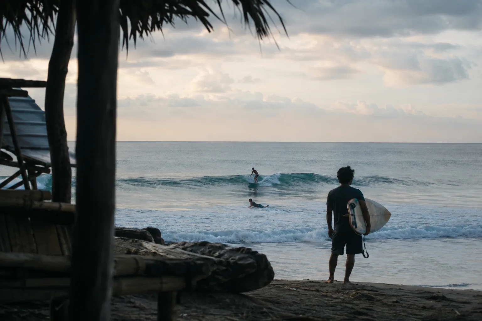 A surfer watching a gentle Indonesian lineup at dawn